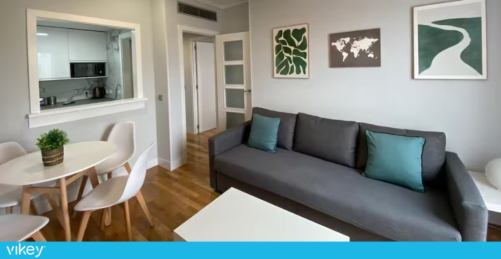 Soggiorno moderno e luminoso di un appartamento LiveTheCity a Madrid con divano grigio e arredi minimal.
