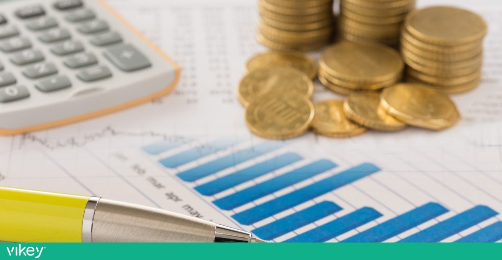 Grafico finanziario con monete e calcolatrice per analizzare costi e tasse nelle strutture extralberghiere